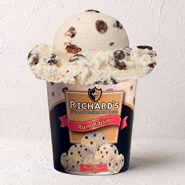 A scoop of Richard's Rum Raisin ice cream overflowing from its branded pint container.
