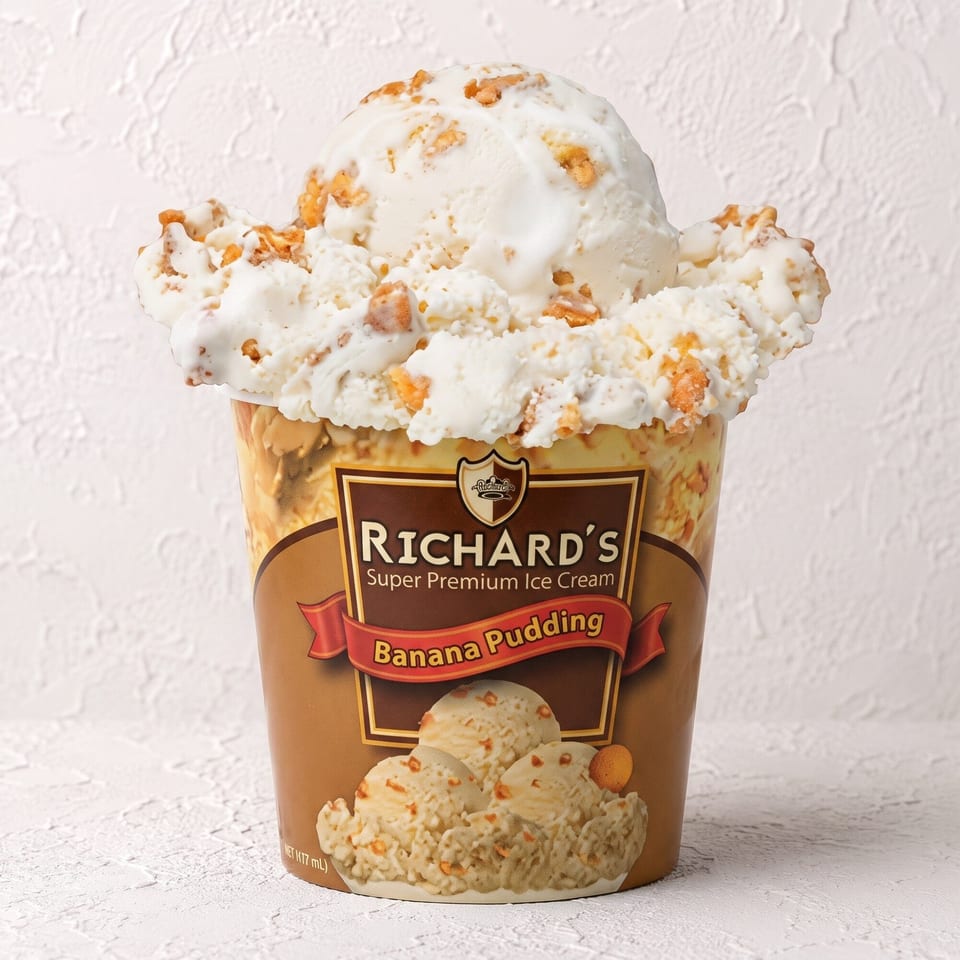 A pint of Richard's Banana Pudding ice cream, overflowing with scoops and crunchy bits.
