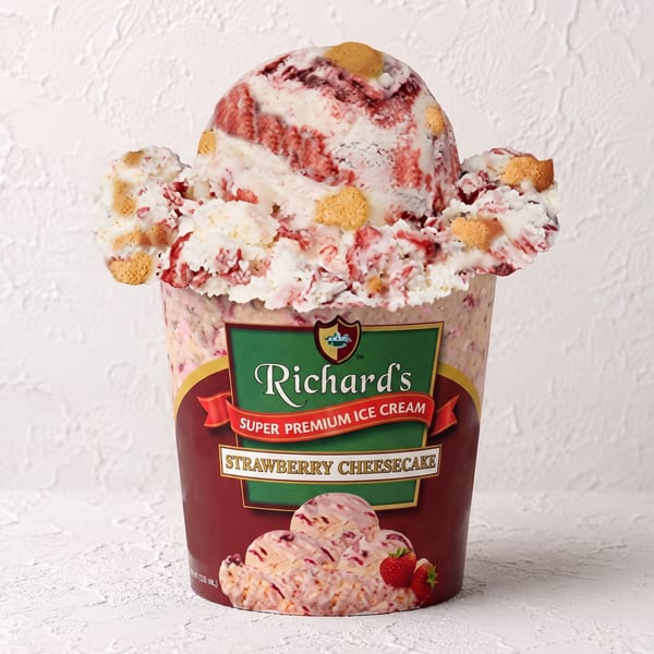 A pint of Richard's Strawberry Cheesecake ice cream with a large scoop overflowing from the top.